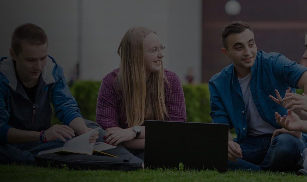 custom-website-design-company-AUBG students sitting on a lawn with a laptop and talking